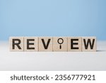 Small photo of Wooden blocks with word Review. Customer review concept. Reviewing, auditing, reviewer. Service rating. Feedback. Review text and magnifying glass on wooden cube blocks