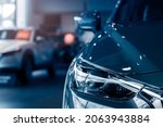 Blurred grey car parked in luxury showroom. Closeup new car parked in modern showroom. Automobile leasing and insurance background. Automotive industry. Auto leasing business. Electric vehicle.