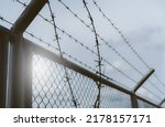 Small photo of Prison security fence. Border fence. Barbed wire security fence. Razor wire jail fence. Boundary security wall. Prison for arrest of criminals or terrorists. Private area. Military zone concept.