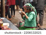 Small photo of MEO VAC, VIETNAM- November 1, 2015: woman from a Vietnamese ethnic group wearing traditional colorful clothing, having lunch in the covered market of the township of Meo Vac, Northeast Vietnam.