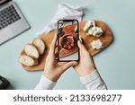 Top view of young woman taking aesthetic photo of food using smartphone in home studio, copy space