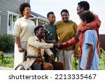 Side view portrait of big African American family with person in wheelchair welcoming guests for Summer party