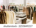 Small photo of Background image of luxury boutique interior at shopping mall with clothes on hangers, copy space