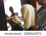Closeup of unrecognizable woman brushing wig by mirror at home, copy space