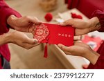 Small photo of Close up of two people handing ornate red envelope as Chinese New Year tradition for good luck Have overflowing abundance every year