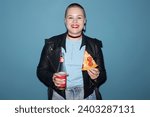 Small photo of Medium shot of cheerful young girl with buzz cut holding slice of pepperoni pizza and bottle of lemonade while standing at light blue background