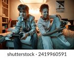 Small photo of Portrait of two teenagers playing videogames together at night and having fun