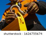 Closeup picture of rigger high risk worker wearing safety heavy duty glove, safety helmet fastening pin into D- shape shackle into crane lifting lug gate prior lift at construction site Perth city
