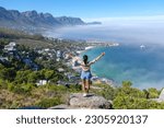 Small photo of women with hands up at The Rock viewpoint in Cape Town over Campsbay, view over Camps Bay with fog over the ocean. fog coming in from the ocean at Camps Bay Cape Town South Africa