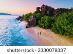 Small photo of Anse Source d'Argent beach, La Digue Island, Seyshelles, Drone aerial view of La Digue Seychelles bird eye view.of tropical Island, couple men and woman walking at the beach during sunset at a luxury
