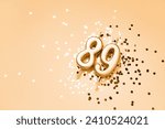 Small photo of 89 years celebration festive background made with golden candles in the form of number Eighty-nine lying on sparkles. Universal holiday banner with copy space.