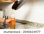 Close up of a man's hands recycling edible oil from a frying pan into a plastic bottle in his home kitchen. Recycling concept at home. . High quality photo