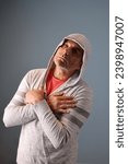 Small photo of Lethargic adult male wearing hoody crossing fingers on his chest and looking off camera