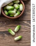 Small photo of Small fresh snack cocktail Dutch cucumbers Quirk variety on wooden background, healthy vegetarian organic food concept