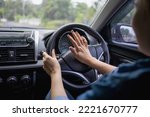 Woman pushing horn while driving sitting of a steering wheel press car, honking sound to warn other people in traffic concept.