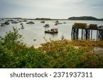 Small photo of Cape Porpoise, Maine-USA, September 5, 2023: Maine fishing boats are moored in the harbor at low tide with lobster traps on stacked on the commercial dock.