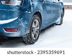 Back view of blue car covered with snow parked on snow covered road.