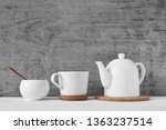 Cup of tea, teapot and sugar bowl on gray background