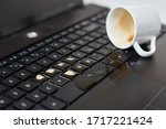 Spill coffee from white cup on computer laptop keyboard.Damage to computer due to spilled liquid