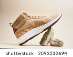 Male boots on beige background. Winter shoes on stone platform