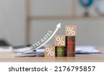 Small photo of Interest on stacks of US dollars on a wooden table with an arrow pointing up. Finance and Mortgage Interest Rate Ideas wooden block with percentage icon and arrow pointing up the economy is improving