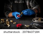 Master plumber connects brass fittings when repairing equipment or installing gas. Close up of gloved hands of foreman while working in workshop.