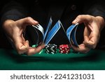 Small photo of Masterly shuffling of playing cards with the hands of a dealer or croupier in a poker club on a green table with playing chips. Casino game concept.