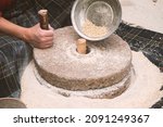 The ancient hand mill or quern stone, grinds the grain into flour. Old handmade grinding stones. The old woman is grinding flour with the traditional method.
