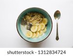 Blue healthy breakfast bowl with musli banana chia seeds and yoghurt with spoon isolated on white bacground