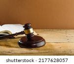 Judgment and justice. Judge's gavel on a wooden table and an open book on a beige background. Rule of law, fair trial, constitution, presumption of innocence.