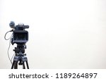 The video camera is standing on the tripod isolated on white.