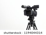 The video camera with the microphone is standing on the tripod isolated on white, in concept of technology, modern, entertainment.