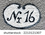 Small photo of Close up of a house number 16 painted on roughcast on a house wall