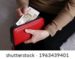 Small photo of Elderly woman takes out russian rubles from her wallet, wrinkled female hands closeup. Concept of poverty in Russia, pension payments, pensioner
