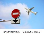 Small photo of Stop sign with down arrow and airplane in blue sky. Concept of band on flights over Europe from Russia, sanctions due to the russian special military operation in Ukraine