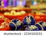 Christmas toys, blue balls with bunny - symbol of Chinese New Year 2023 on blurred festive lights background. New Year decorations in a store