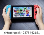 Small photo of Marmaris, Turkey - October 22, 2023: Girl playing Super Mario Bros. Wonder game on Nintendo Switch console in handheld mode, selective focus on a screen