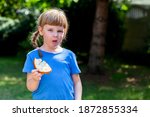 Small photo of Fussy eater, little girl, picky child eating a slice of bread with butter displeased, choosy kid behavior, doesn't want to eat, refusing a meal, food aversion, rebel, children grimaces, making faces