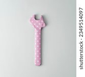 Small photo of Wrench wrapped in pink polka dot gift paper on blue background. Top view.