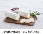 Goat cheese on a wooden board on a light background.