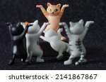 Small photo of Toy kittens bow before the ginger cat. The concept of election and popularity. The concept of sycophancy, servility and totalitarian power, hypnosis and suggestion. Selective focus. Black background
