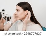 Otoplasty is surgical reshaping of the pinna, or outer ear for correcting an irregularity and improving appearance. Surgeon doctor examines girl ear before otoplasty cosmetic surgery