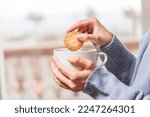 Woman hands dipping cookie into coffee cup	