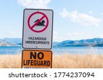 Small photo of Hazardous undercurrents warning sign on beach at lake