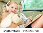 Small photo of Girl with cuddly toy and headphones in the car listens to music or an audiobook