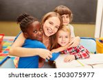 Small photo of Young woman as a childminder or teacher hugs children in daycare or elementary school