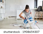 Small photo of Woman as a handyman at home painting a chair or painting as upcycling