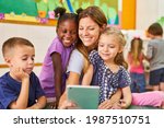 Small photo of Childminder and children take a selfie with the tablet computer in kindergarten or after-school care center