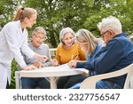 Small photo of Group of happy senior friends solving crossword puzzle and maze in garden of nursing home0