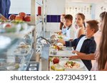 Small photo of Happy kids in line taking food from cafeteria worker during lunch time at school